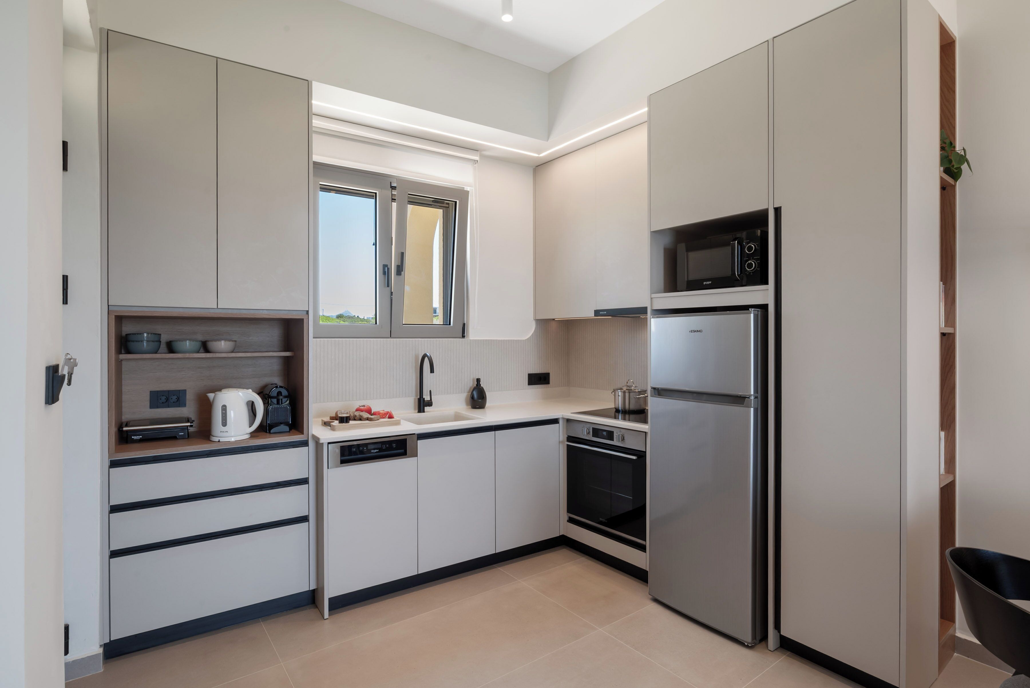 A modern kitchen with built-in appliances, a window, and a view of the outdoors.