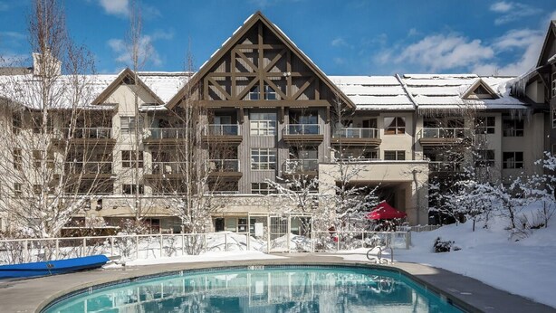 A hotel with a large pool, multiple balconies, and a snow-covered landscape.