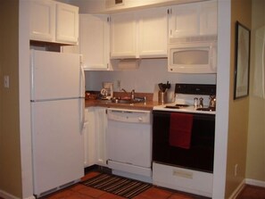 Kitchen features a refrigerator, dishwasher, microwave, and oven, along with a tiled backsplash and wooden countertop.