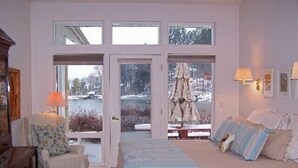 Ett sovrum med en stor säng, en stol, en byrå och ett fönster med utsikt över ett snötäckt landskap.