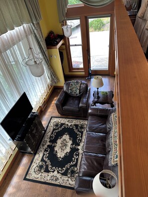 A living room with a sofa, a coffee table, a TV, and a patterned rug. - Lieutenant's Suite - Romantic Luxury 1 Bedroom Loft, Easy Access to Beach & Town (Eastsound)