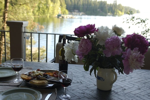 A dining table with a meal, wine glasses, and a vase of flowers.