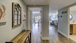 A hallway with a wooden bench, a fish-themed wall decoration, and a door leading to a dining area. - 404 Captain's Walk: Perfect 2BR/2Bth Oceanfront Condo (Hilton Head Island)