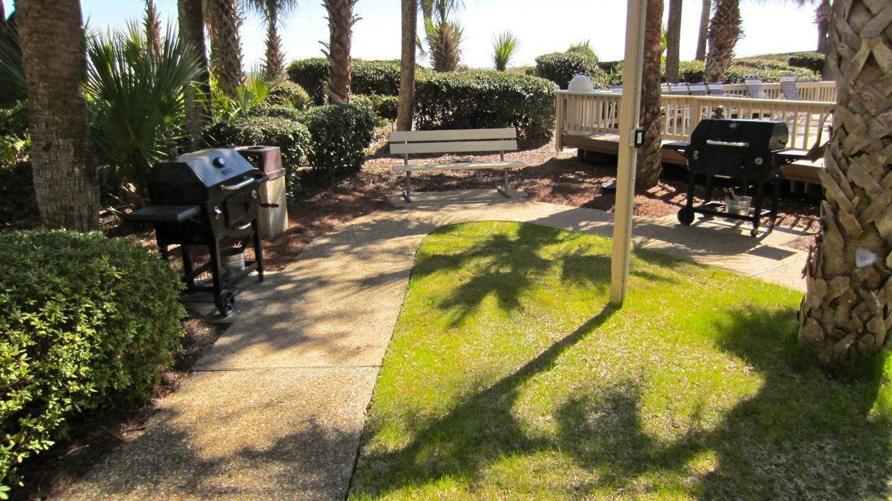 Un espace extérieur aménagé avec un barbecue, un banc et une table.