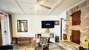 Ein Wohnzimmer mit Kamin, Wandfernseher und einer Bank.