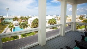 A covered balcony with a view of a swimming pool and palm trees. - Waterfront Home with Golf Cart, Kayaks, Bikes and Paddleboards! (Navarre Beach)