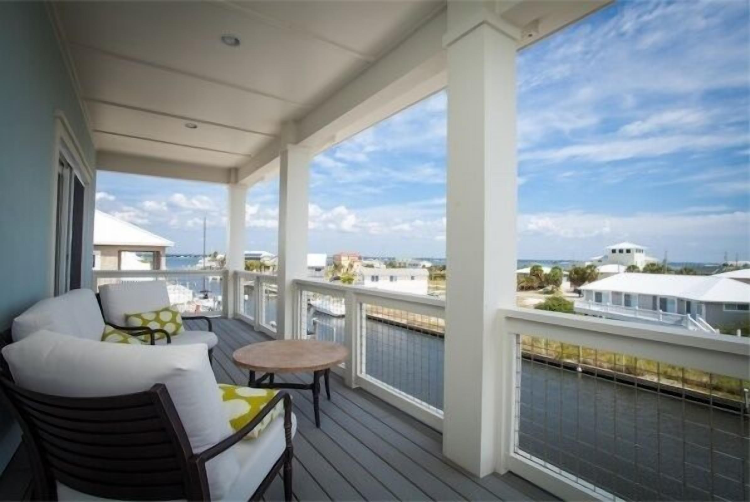 A covered balcony with a view of the sea and other buildings.