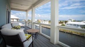 A covered balcony with a view of the sea and other buildings. - Waterfront Home with Golf Cart, Kayaks, Bikes and Paddleboards! (Navarre Beach)