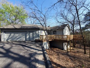 A two-story house with a garage, a wooden deck, and a covered porch.