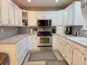 A kitchen with white cabinets, stainless steel appliances, and a built-in oven.