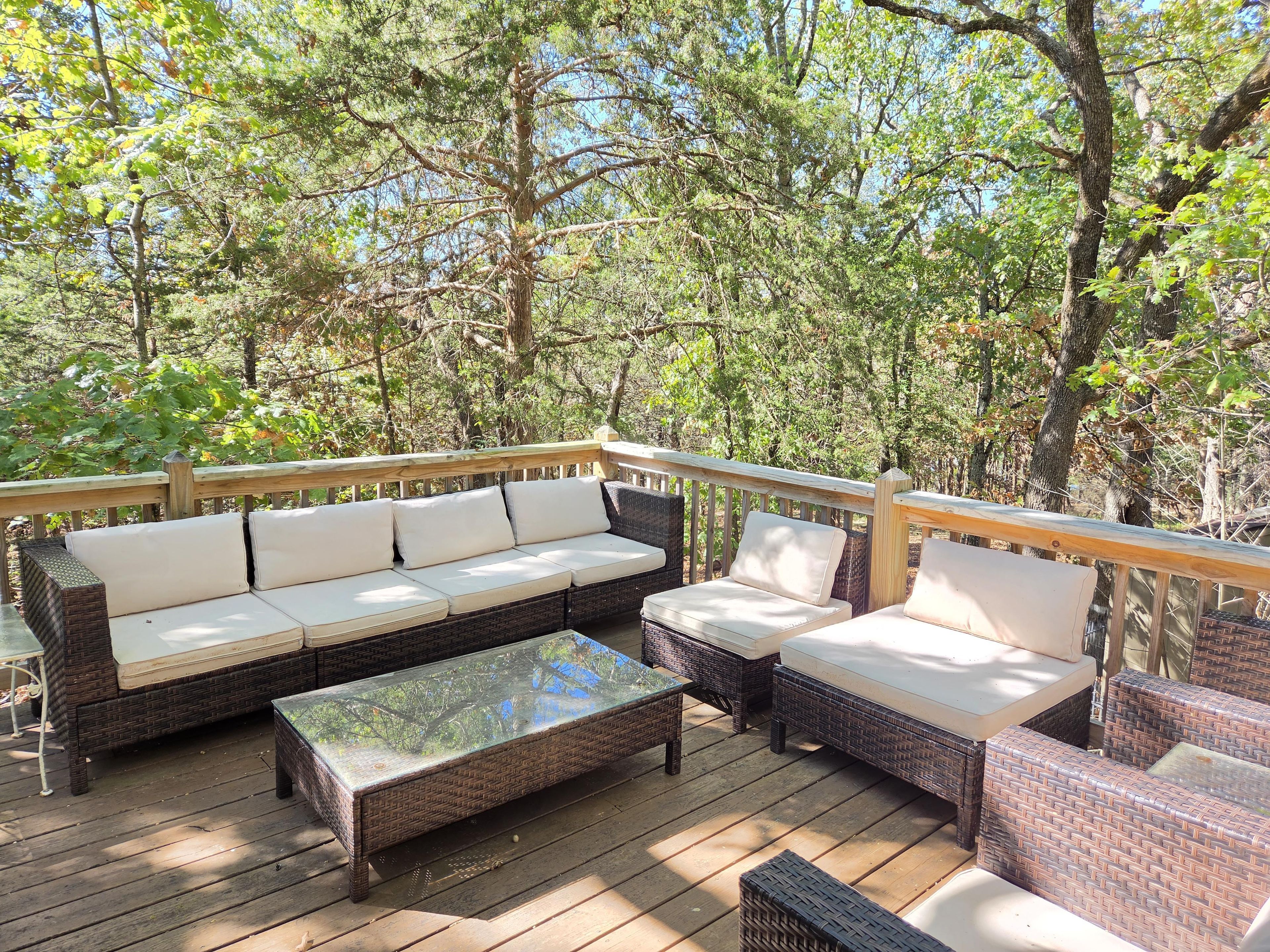 Terraza exterior con mobiliario de mimbre y una mesa con superficie de vidrio.