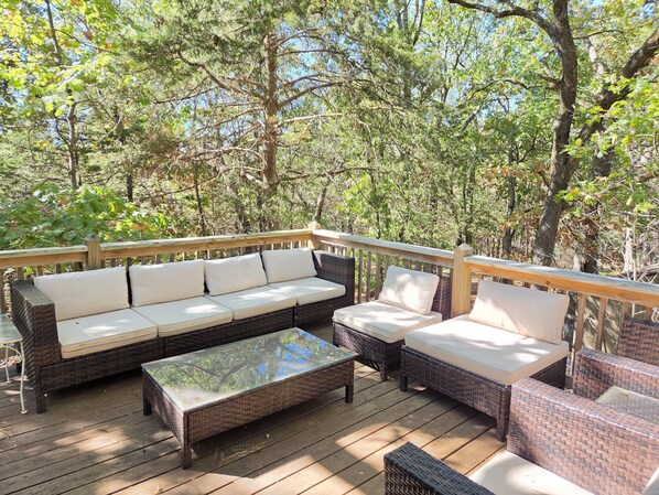 An outdoor deck with wicker furniture and a glass-top table.