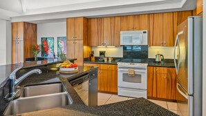 A modern kitchen with wooden cabinets, stainless steel appliances, and a granite countertop. - Walk to Beach & Sunset-Luxury - Golf Course -2000sq ft - 3BR Pool&Jacuzzi (Princeville)