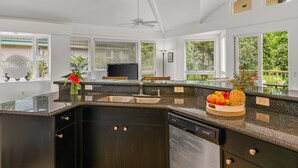 A modern kitchen with a granite countertop, stainless steel appliances, and a large window offering a view of greenery. - Walk to Beach & Sunset-Luxury - Golf Course -2000sq ft - 3BR Pool&Jacuzzi (Princeville)
