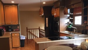A kitchen with wooden cabinets, a black refrigerator, and a dining area with a round table and placemats. - Scenic View Of Lake Yet Close To The Wonderful Charm Of Nashville (Mount Juliet)