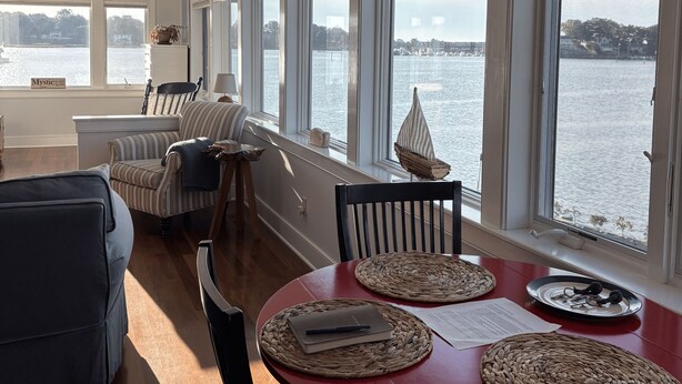 A dining area with a red table, woven placemats, and a view of the water. - Oyster lovers wanted! One of a kind property with 180 degree waterviews! (Mystic)