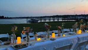 A table set for a meal with a view of the water and a dock in the background. - Oyster lovers wanted! One of a kind property with 180 degree waterviews! (Mystic)