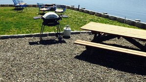 A lakeside patio with a grill, chairs, and picnic tables. - Oyster lovers wanted! One of a kind property with 180 degree waterviews! (Mystic)