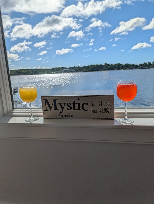A window view of Mystic, Connecticut, with two glasses of drinks on the windowsill.