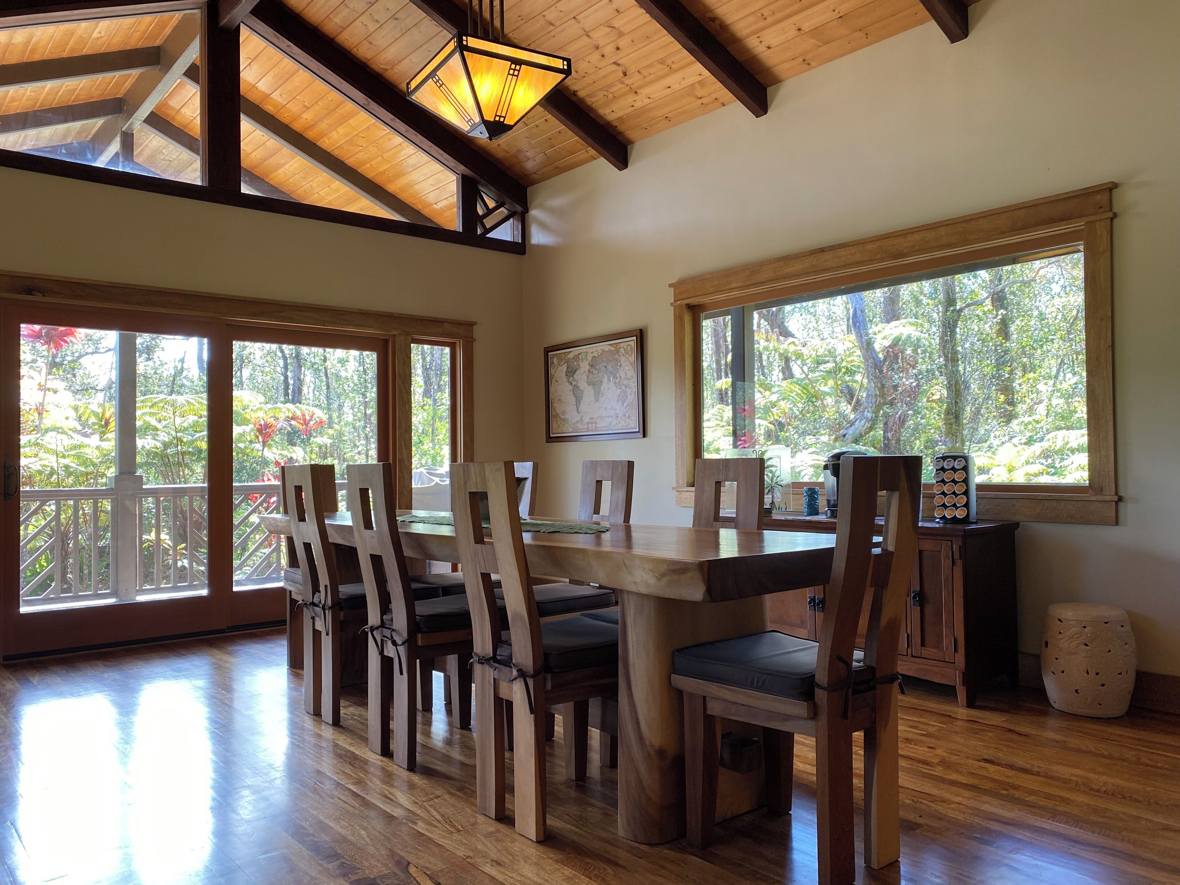 A dining area with wooden furniture, large windows, and a wooden ceiling.