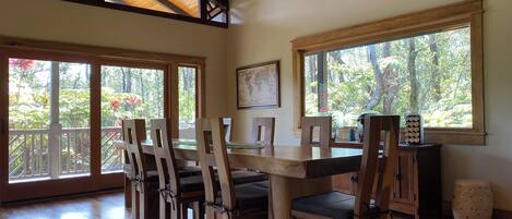 A dining area with wooden furniture, large windows, and a wooden ceiling.