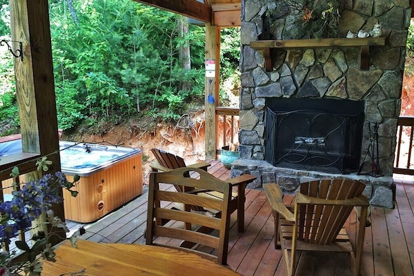 Outside fireplace (firewood provided), dining table, and hot tub.