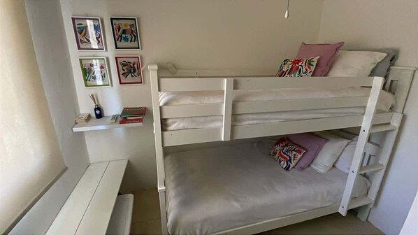 A bunk bed room with a shelf above the lower bunk and a desk with books. - Punta Mita Ground-Floor Condo w/ Pool & Beach Access (Punta de Mita)