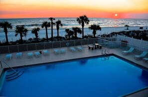 A swimming pool with lounge chairs and a view of the ocean at sunset. - Newly renovated, gated, 2 parking spots, 11 pools, gym, shuffleboard, putt-putt (Panama City Beach)