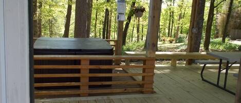 Une terrasse en bois avec un jacuzzi, une table de pique-nique et un panneau indiquant une zone de sécurité.