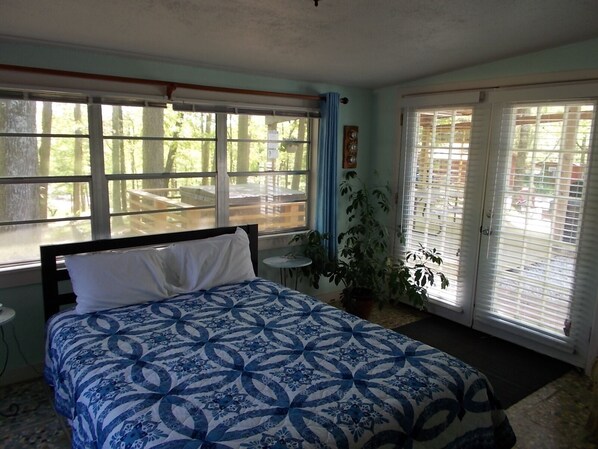 A bedroom with a bed, a window, a door, and a potted plant.