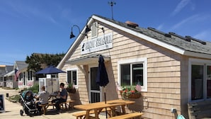 Una tienda de esquina llamada 'Sandy Seagull' con asientos al aire libre y banderas estadounidenses.