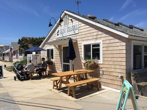 Enjoy casual dining and socializing at Sandy Seagull Corner Store's outdoor space with picnic tables and benches.