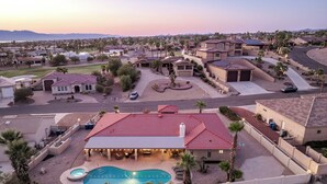 A residential area with a swimming pool, houses with red-tiled roofs, and a hilly landscape in the background. - Tail wags welcome! Close to Lake, Boat and RV Parking! (Lake Havasu City)