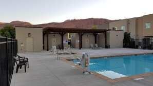 Una piscina al aire libre con un puesto de salvavidas, sillas de descanso y una zona de estar cubierta.