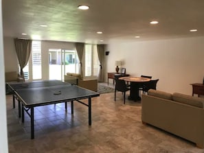 Un grand espace de vie comprenant une table de ping-pong, une table à manger ronde et un canapé.