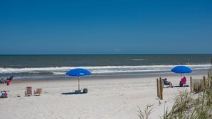 A beach with two blue umbrellas, a sandy shore, and the ocean in the background. - Surf & Racquet Club A124-Condo (Fernandina Beach)