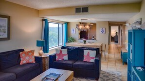 A living room with a sofa, coffee table, and a dining area with a table and chairs. - Surf & Racquet Club A124-Condo (Fernandina Beach)