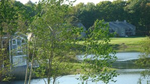 A lakeside view with a house, trees, and a sign indicating a private property.