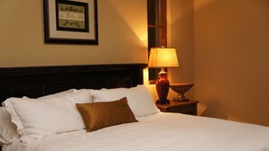 A neatly made bed with white linens and a brown pillow, a framed picture on the wall, and a table lamp on a bedside table. - Villa della Luna, an authentic Tuscan Villa in Montaluce, license #3857 (Dahlonega)