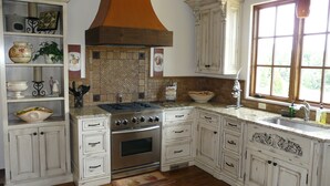 A kitchen with white cabinetry, a stove, and a window. - Villa della Luna, an authentic Tuscan Villa in Montaluce, license #3857 (Dahlonega)