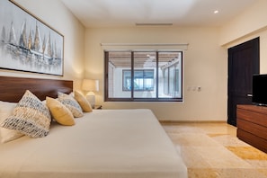 A hotel room with a large bed, a window with blinds, a painting on the wall, and a TV on a wooden dresser.
