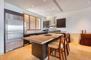 A modern kitchen with a large island, stainless steel appliances, and dark wooden cabinetry.