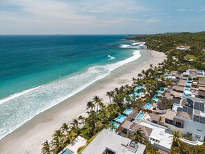 A coastal resort with beachfront properties, swimming pools, and palm trees. - Beach Front Condo w/ Balcony! Amazing Views, White Sand & Pools! (Punta Mita)