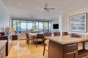 Une cuisine moderne dotée d’un îlot central, d’un coin repas avec des chaises et d’une grande fenêtre offrant une vue sur l’extérieur.