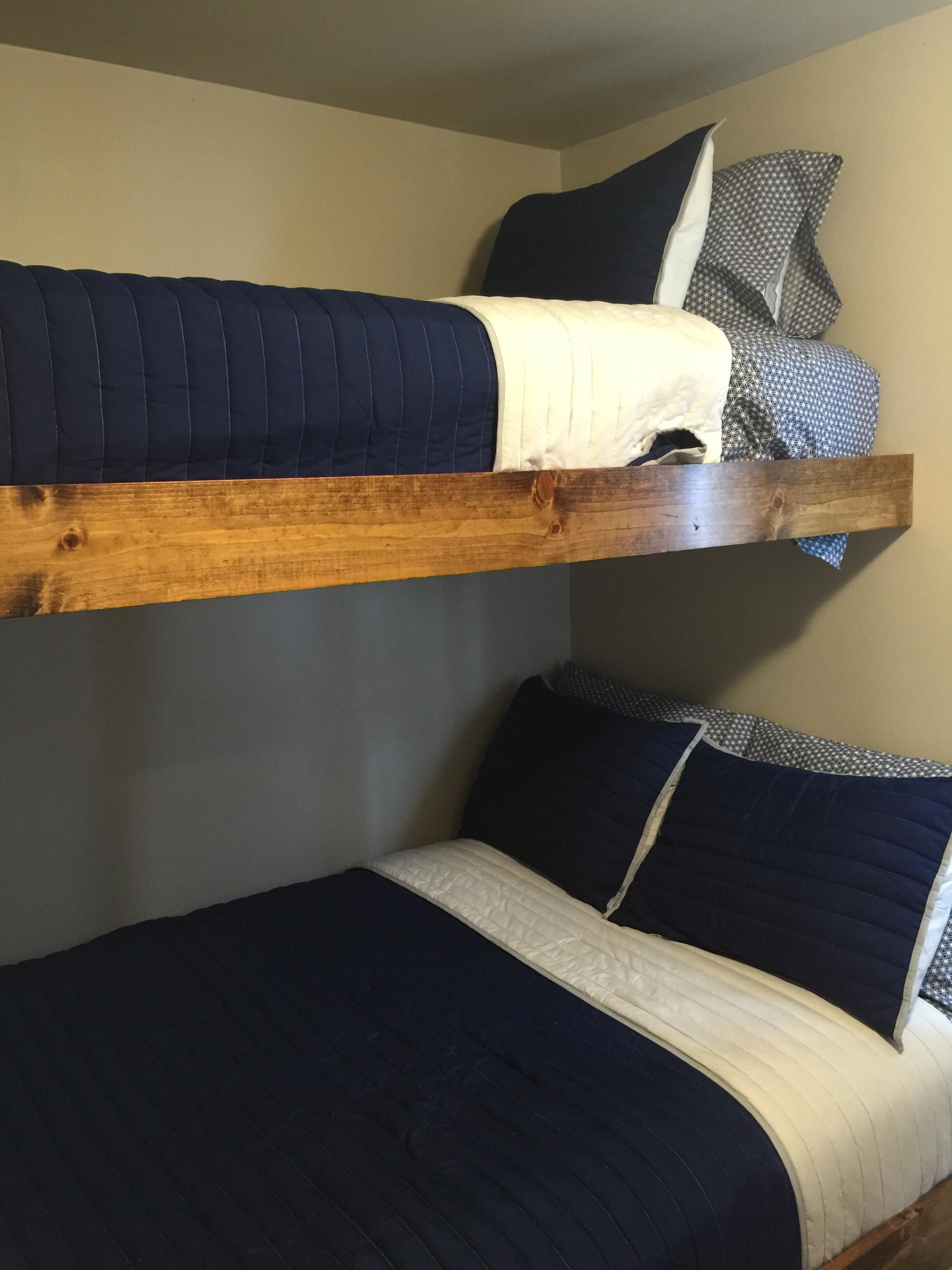 A bunk bed with a wooden frame, two pillows, and a patterned blanket.