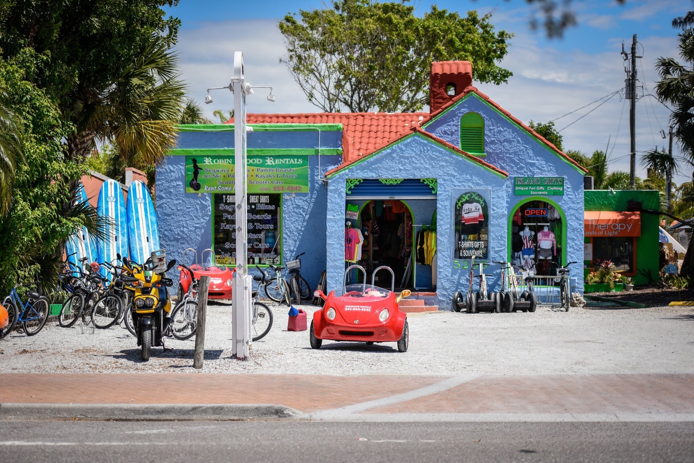 A colorful building with a sign for 'Island Gifts' and a red toy car in front.