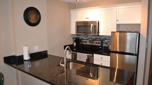 A modern kitchen with stainless steel appliances, a granite countertop, and white cabinetry. - Ski In Ski Out Great Location Hot Tub Super Clean Fully Stocked Great Reviews (Whistler)