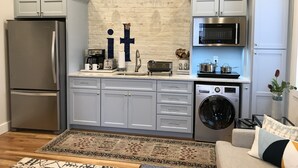 Une cuisine compacte équipée d’un réfrigérateur, d’un four à micro-ondes, d’un évier et d’un lave-linge.