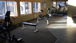 A gym with exercise equipment, large windows, and a view of the outside.