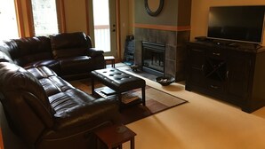 A living room with a fireplace, leather sofas, a television, and a small table.